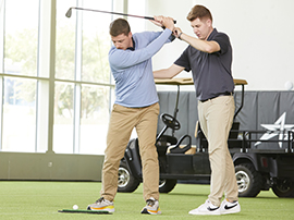 A guy works on  the form of his golf swing with the help of an instructor.