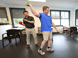 A man works on his overhead throwing skills with his physical therapist.