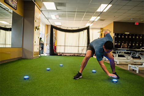 Athlete performing a drill to improve speed and reaction time using light up devices on a field