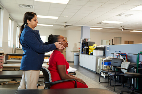 TMJ patient is sitting in chair while therapist is checking on head and neck