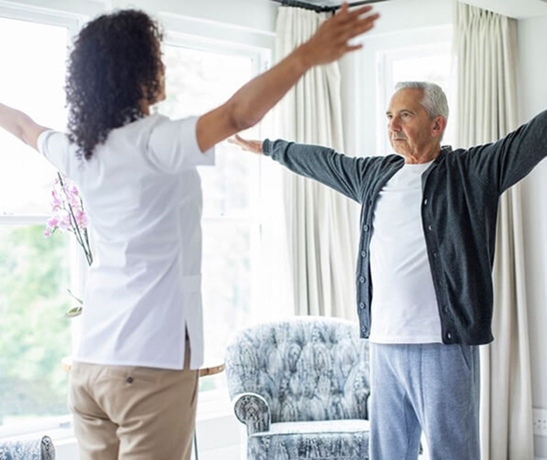 Therapist doing stretches with a patient in his home.