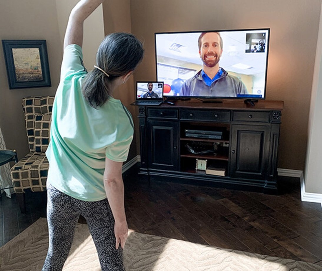 therapist helping a patient via telerehab session