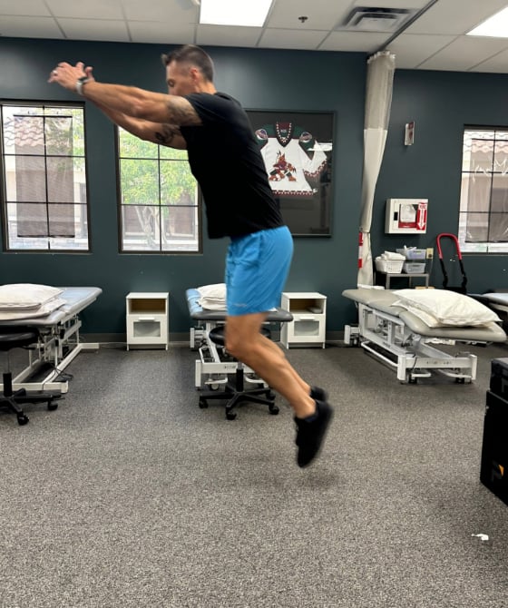 A male physical therapist jumping forward in the air. 
