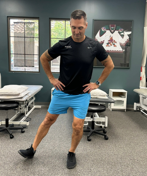 A male physical therapist with his right leg stretched outwardly in the shape of a Y. 