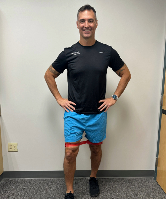 A male physical therapist with an exercise band around his quads. 
