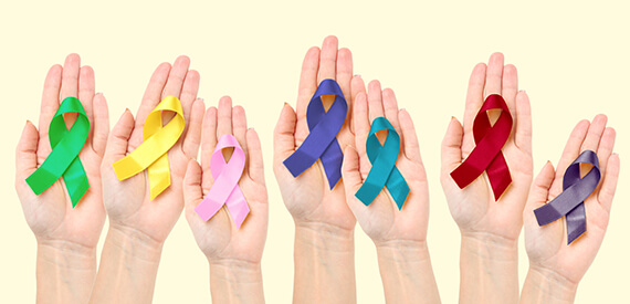 Seven hands are holding the various cancer ribbons representing different types of cancer
