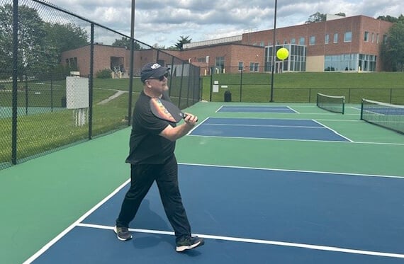 Dan on the pickleball court mid swing at an oncoming pickleball
