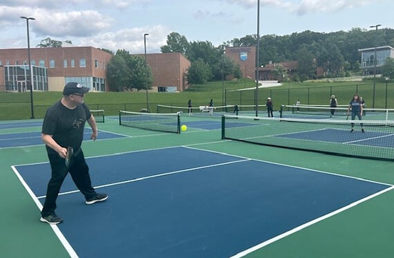Dan on the pickleball court mid swing at an oncoming pickleball