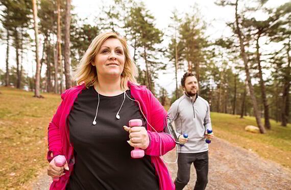 Women and man running outdoors with weights in hand