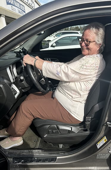 Karen sitting and smiling in the driver's seat of her car