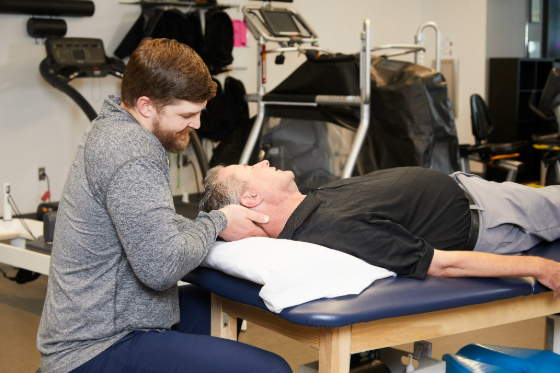 A male patient receiving a neck adjustment from his physical therapist. 