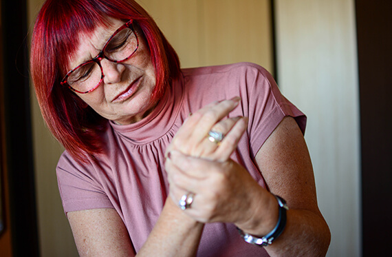 A woman is holding her wrist and has a look of pain on her face