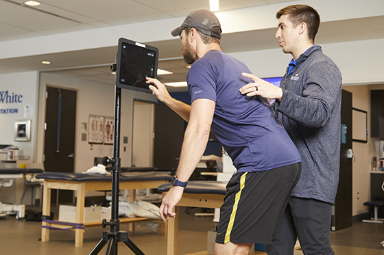 A physical therapy patient doing a movement screen with his physical therapist. 