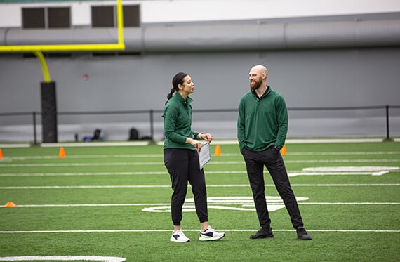 Athletic trainer and physical therapist talking on a football field