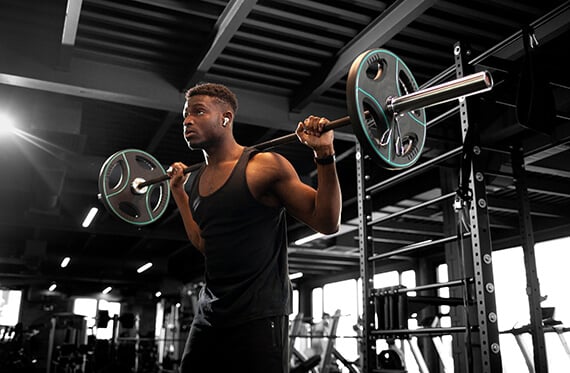 Man in a gym weightlifting with a barbell on his shoulders