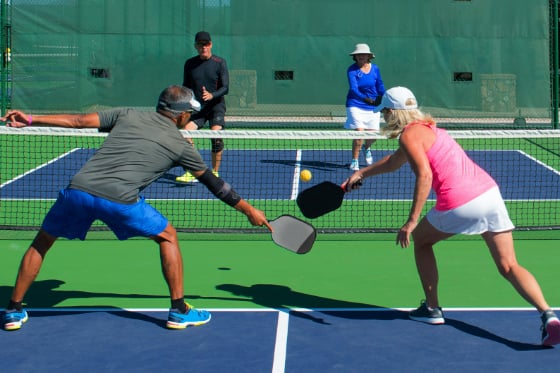 Two pairs of couples playing a game of pickleball. 