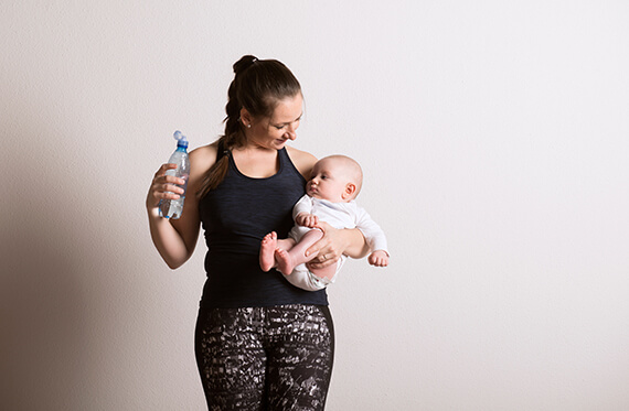 A mother is holding and smiling at her baby with a water bottle in the opposite hand