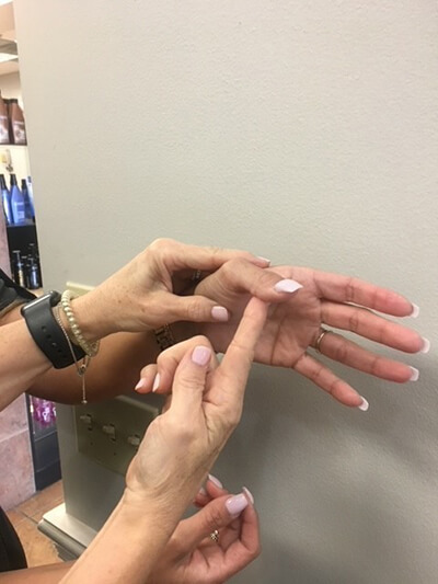 close-up of a person's hand with their finger being stretched by a therapist