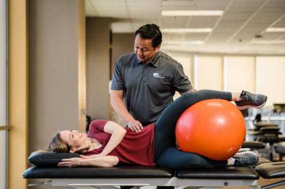 A male physical therapist doing pelvic floor exercises with a female patient. 