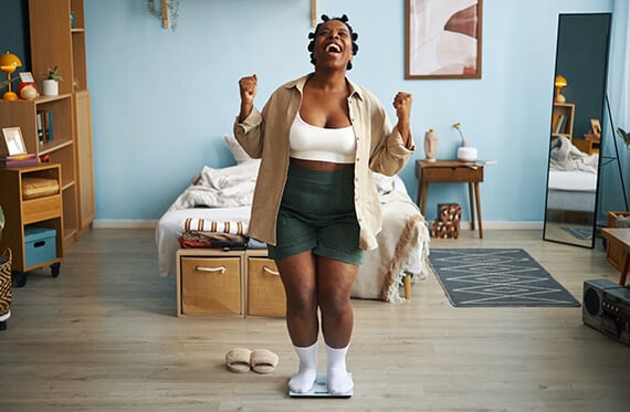 Women standing on a scale with a happy expression and cheering