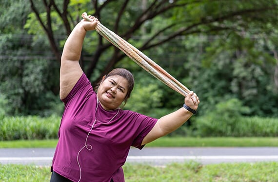 Woman holding a band above her head and stretching her torso to one side